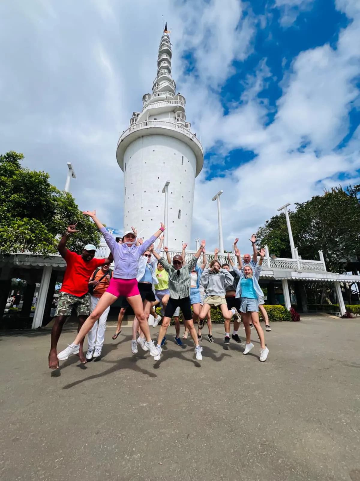 A group jumping for a photo in front of Ambuluwawa Tower