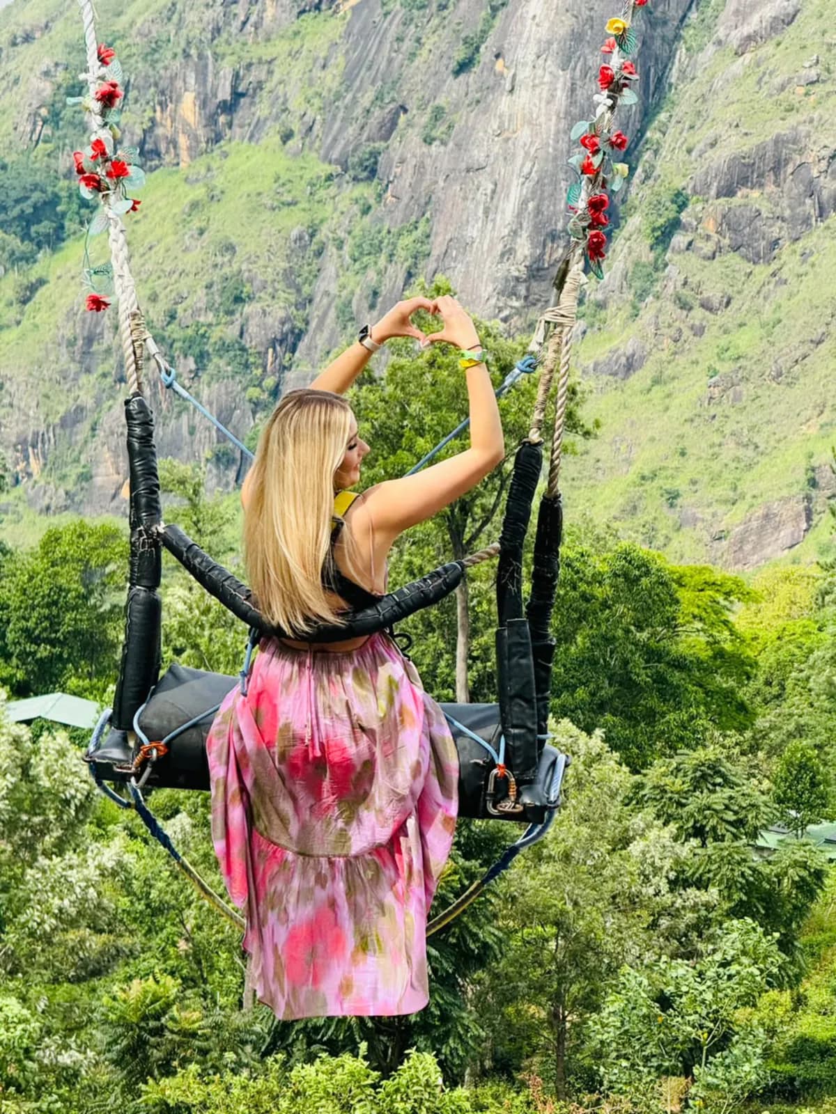 A traveller on a swing above a green mountain gorge