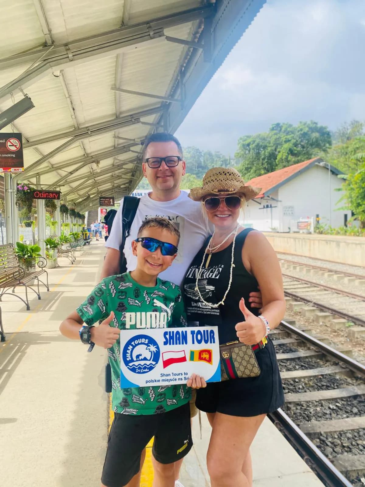 A family with the Shan Tours board at a hill-country railway station