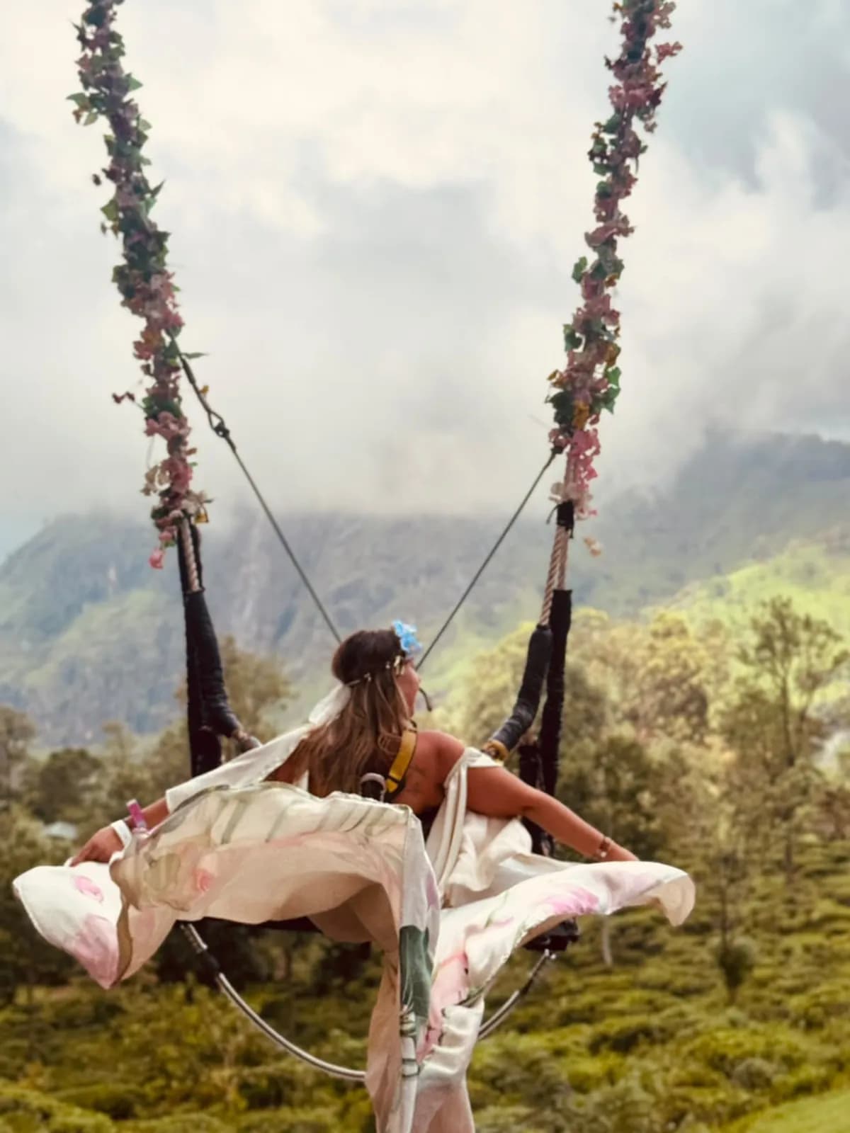 A traveller on a flower swing above misty highland valleys