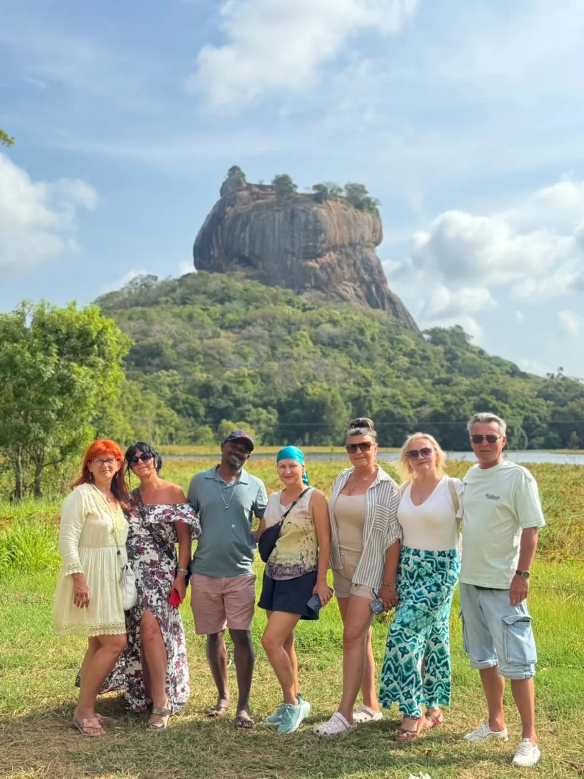 A group of travellers on the grass below Sigiriya rock fortress