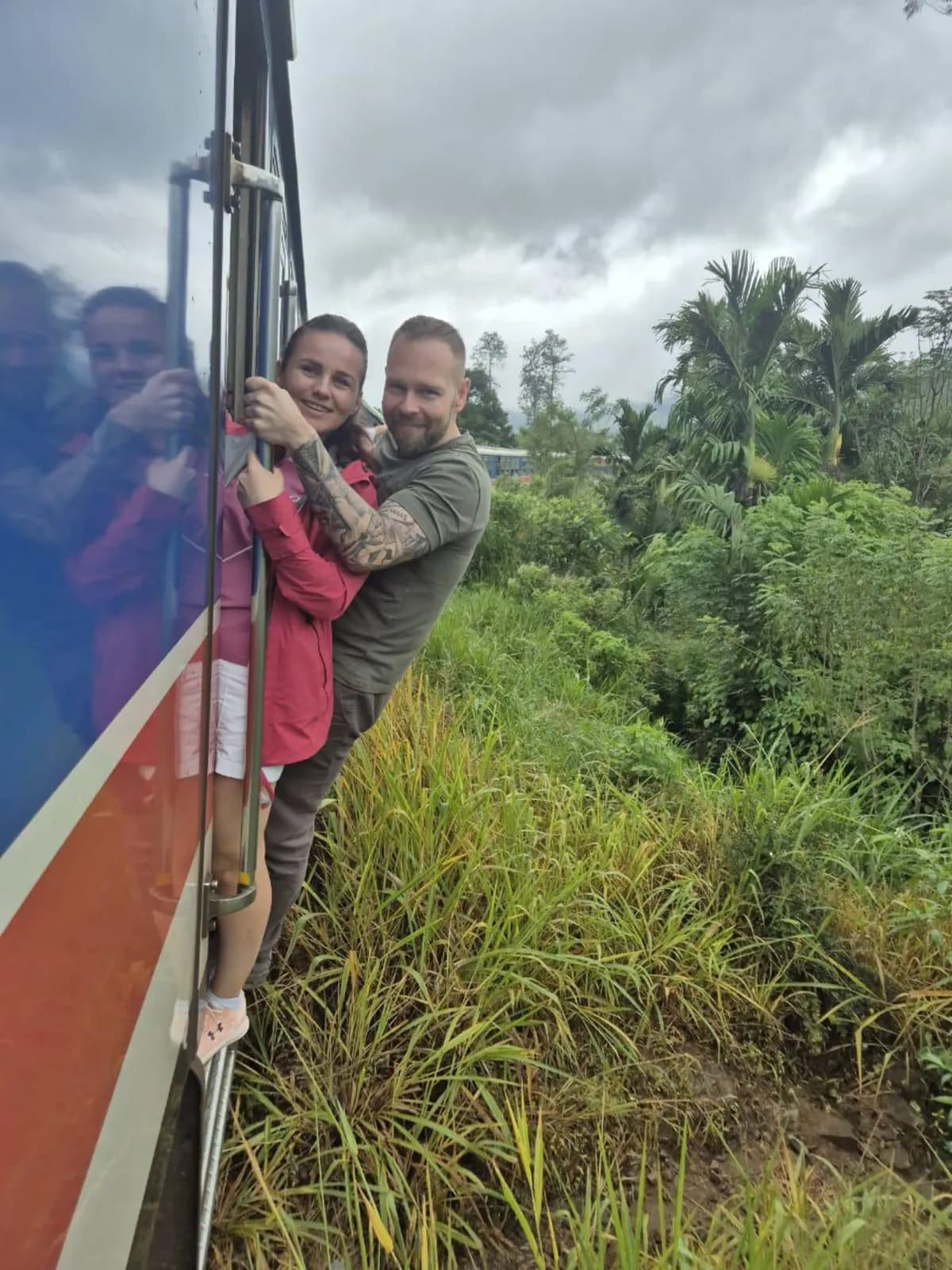 Two travellers hanging from the doorway of a moving train