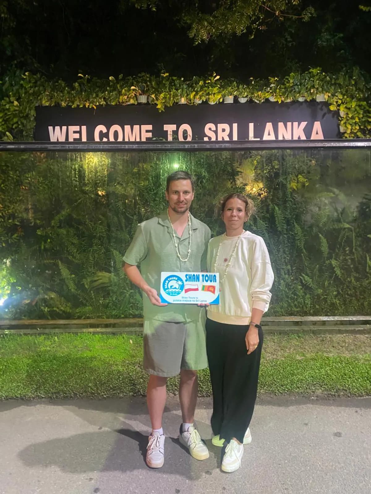 A couple with the Shan Tours board at the Welcome to Sri Lanka sign